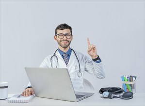 Smiling doctor with laptop with finger up in idea gesture. Doctor sitting with laptop pointing up