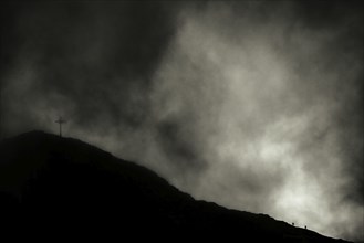 Summit of the Sulzfluh with ascending mountaineers and dramatic cloudy sky, Tschagguns, Rätikon,