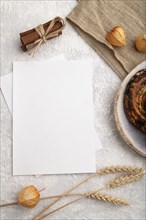 White paper invitation card, mockup with ear of wheat, bun, cup of coffee, linen textile, physalis