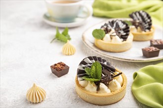 Sweet tartlets with chocolate and cheese cream with cup of coffee on a gray concrete background and