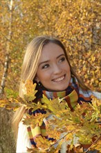 Portrait of young beautiful smiling woman, 30 years old, outdoors in forest with autumn colors in