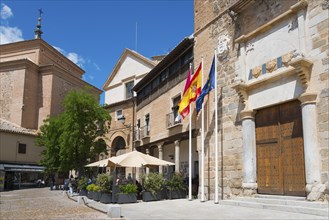 Urban scene with historic buildings, including a church, Spanish and European flags and a cosy