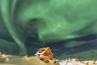 Northern Lights, Aurora borealis over red house, Inuit settlement, Winter, Tasiilaq, East