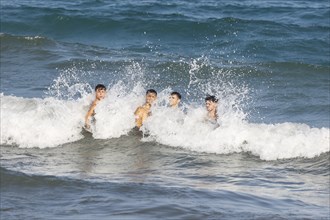 Four young men having fun in the sea, Diano Marina, Italy, 14/08/2024, Diano Marina, Liguria,