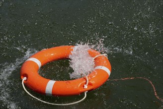 Red lifebuoy with lifeline in the water, distress at sea, drowning, accident, danger, shipping,