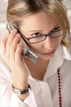 A blonde woman telephoning with Pocket PC, mobile phone, telephone, studio