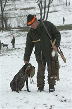 Hunter and hunting dog German Shorthair with hare (Lepus europaeus) and pheasant (Phasianus