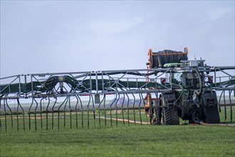 Tractor with boom for spreading liquid manure, on a field, fertilisation