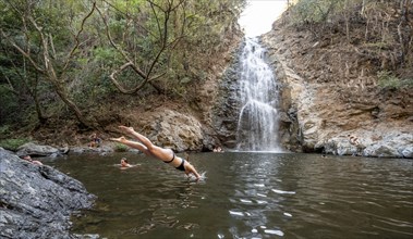 Young woman jumping into the water, Cascada Montezuma waterfall, Montezuma, Nicoya Peninsula,