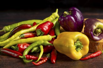 Colourful peppers and chillies arranged on a dark wooden surface, food photography