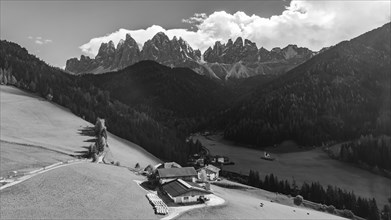 Farm and alpine meadows, in the background the peaks of the Geisler group, drone shot, black and