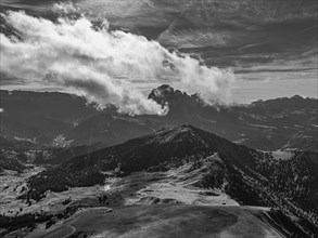 The Picberg, in the background the peaks of the Sassolungo group, shrouded in fog, drone shot,