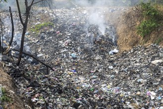 Coking rubbish dump, rubbish pit with waste and plastic rubbish, karst landscape near Vang Vieng,