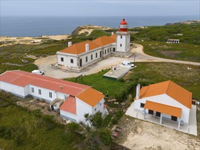 Aerial view of a lighthouse and neighbouring buildings on the coastline, with orange roofs, Farol