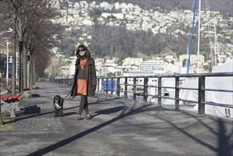 Woman Walking with Her Dog on the City Street in a Sunny Day in Locarno, Ticino, Switzerland,