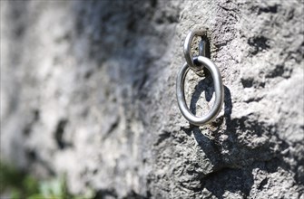 A hook used for sport climbing hangs in a rock face in Morsbach, 09.07.2024