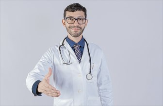 Smiling doctor shaking hands in welcome sign isolated. Friendly male doctor extending hand to