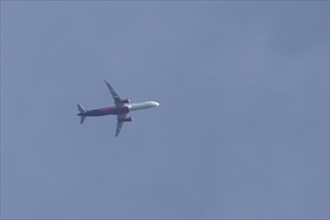 Airbus A320 aircraft of Wizz air airlines in flight across a blue sky, England, United Kingdom,