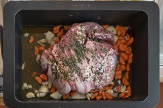 Roast lamb with herbs and vegetables in a casserole in front of roasting, Bavaria, Germany, Europe