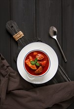 Stew with potatoes, in tomato sauce, with spices and herbs, close-up, no people, on a black