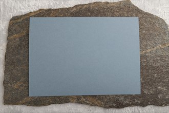 Blue paper business card, mockup with natural stone on gray concrete background. Blank, flat lay,