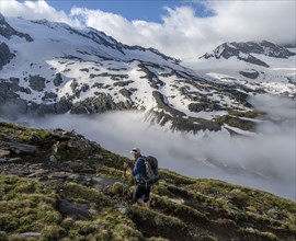 Mountaineers on a hiking trail, high fog in the valley, glaciated mountains with Furtschaglkees