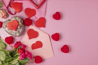 Heart-shaped cake, red hearts and roses around an envelope, Valentine's Day, pink background