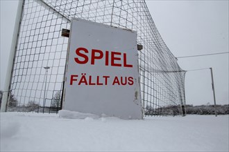 Symbolic image of a football match cancelled due to snow. Sign on a sports field with the