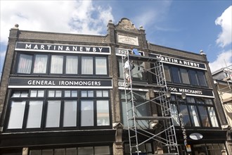 Painters working on scaffolding painting the Martin and Newby ironmongers shop building in Ipswich,