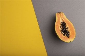 Ripe cut papaya on yellow and gray pastel background. Top view, flat lay, copy space. Tropical,