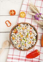 Pearl barley porridge with vegetables in wooden bowl on a white wooden background and linen textile