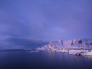 The village of Reine between snow-capped mountains and the sea at dawn, Reine, Moskenesøya,