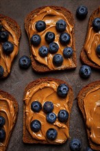 Rye bread with peanut paste and fresh blueberries, top view, no people