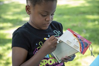 Detroit, Michigan, A girl paints a birdhouse she has put together at the annual 'Summer Sizzler'