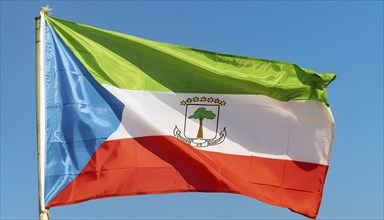 The flag of Equatorial Guinea flutters in the wind, isolated against a blue sky