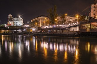 Lights are reflected in the Danube Canal, in the background the illuminated Urania observatory,