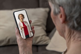 Symbolic image of telemedicine, patient speaks to a doctor in a video conference from home via