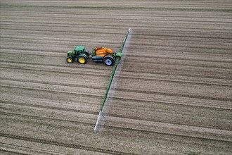 Farmer working a field, crop protection agent being sprayed, field with young sugar beet plants,