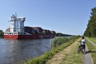 Cyclist and container ship on the Kiel Canal, Kiel Canal, Schleswig-Holstein, Germany, Europe