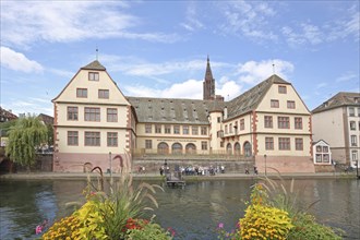 Musée historique, historical museum and river Ill with floral decoration, church tower of the