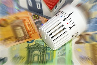 Thermostat and model house on euro banknotes (symbolic image)