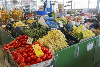 Fresh vegetables displayed on a busy market stall, labelled with price tags, market hall, Fagaras,