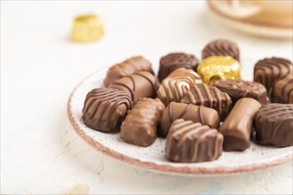 Chocolate candies with cup of coffee and hydrangea flowers on a white concrete background. side