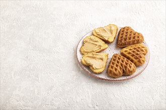 Homemade waffle with peanut butter on a gray concrete background. side view, copy space