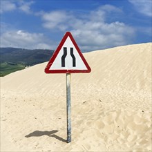 Moving dune with traffic sign, caution narrowed lane, narrowing of lane, dune, coastline near