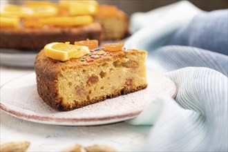 Orange cake with almonds and a cup of coffee on a white concrete background and blue linen textile.