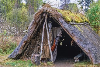 Reconstructed Stone Age hut with thatched roof and benches on an autumn day, Sweden, Europe