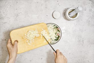 Top view of adding chopped onion into a bowl with minced meat. Making of meatballs