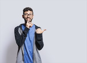 Mysterious person pointing to the side with his fingers on isolated background, Mysterious man