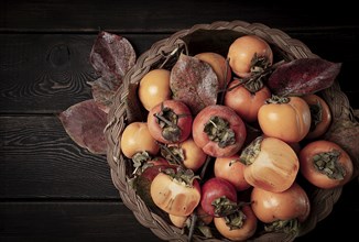 Fresh persimmon in a basket, with leaves, top view, no people